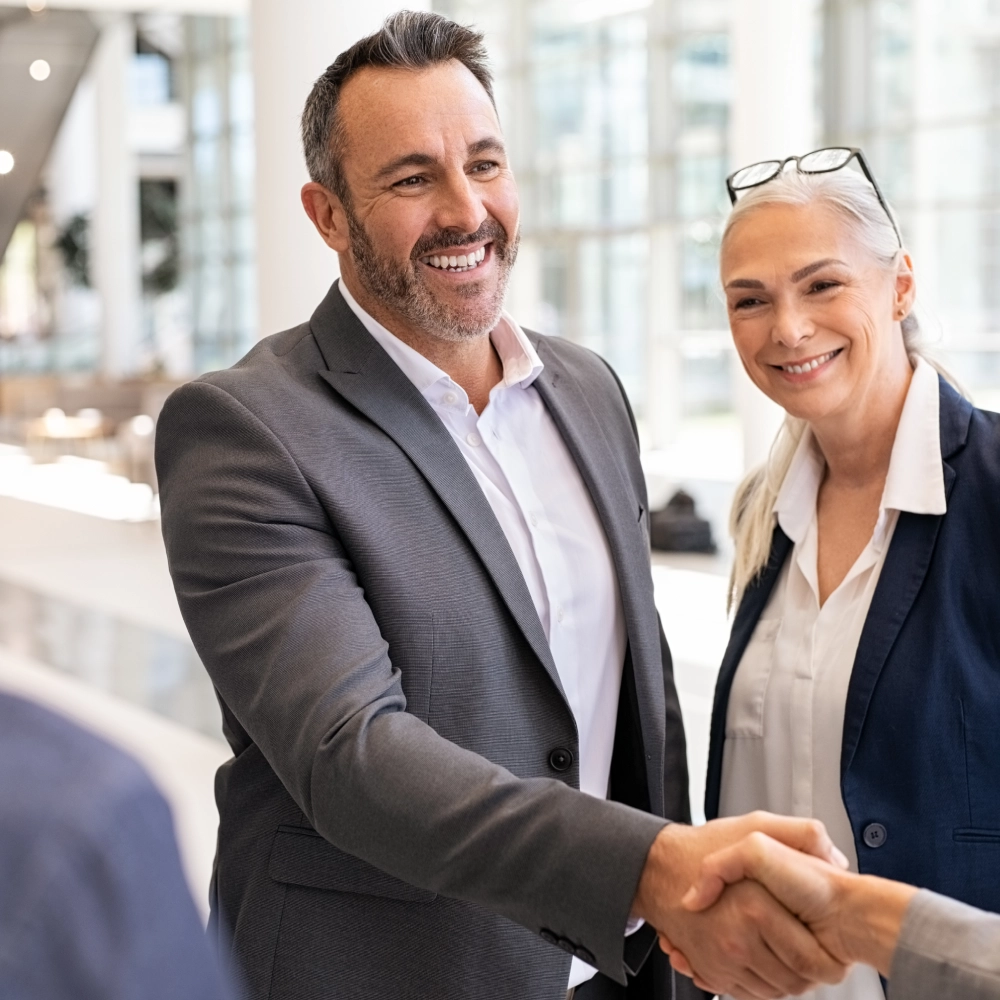 A man and woman shaking hands in front of an audience.