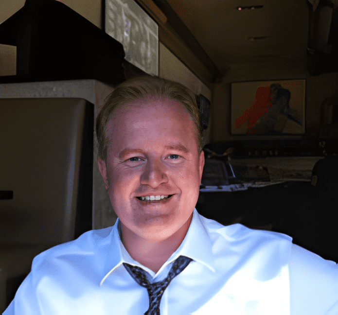 A man in a white shirt and tie smiling.