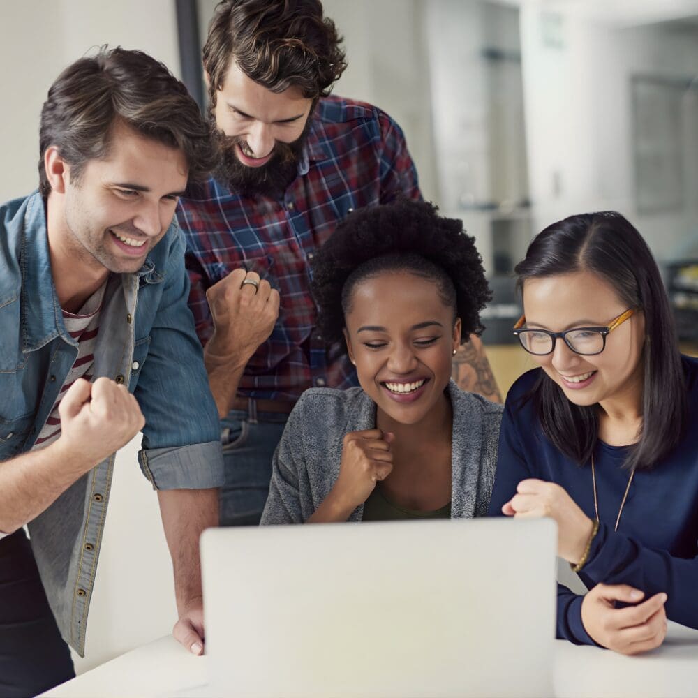 Diverse coworkers celebrating success at laptop