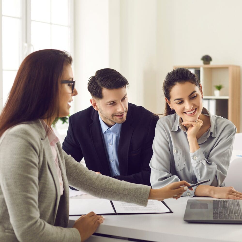 Three colleagues reviewing laptop together in office