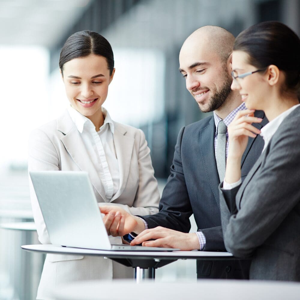 Colleagues collaborating around laptop in office